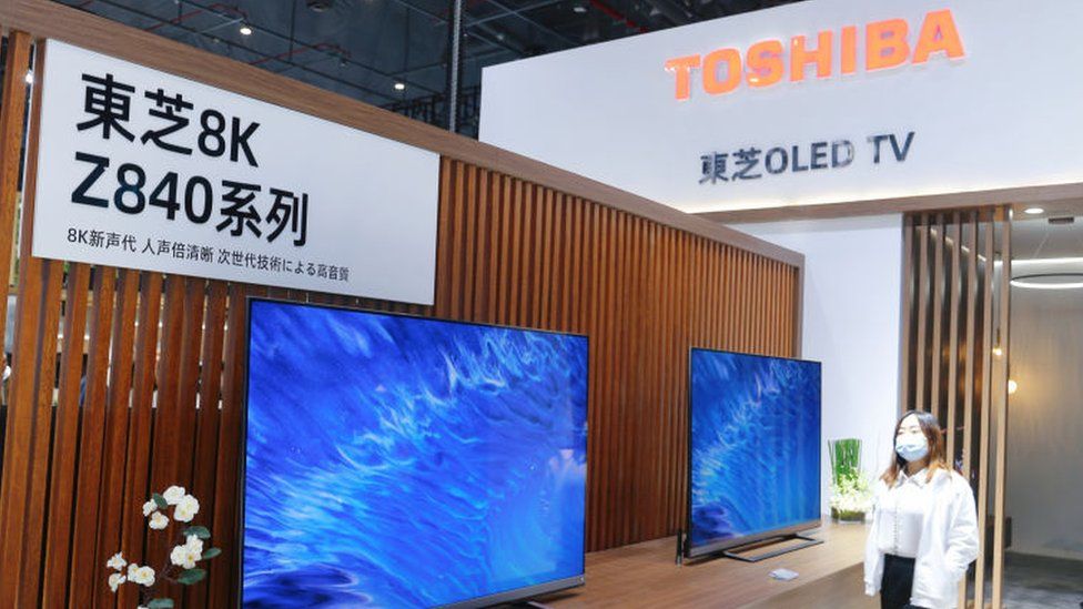 Woman walks past Toshiba 8K TV set