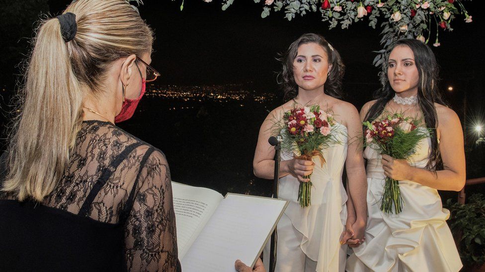 Same-sex newlyweds stand before a lawyer during their wedding