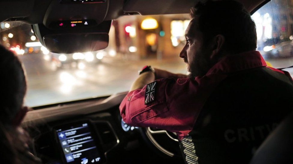 A paramedic drives an ambulance car at night