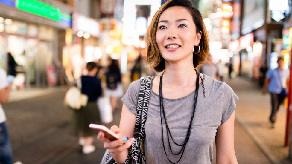 Woman walking in street with smartphone