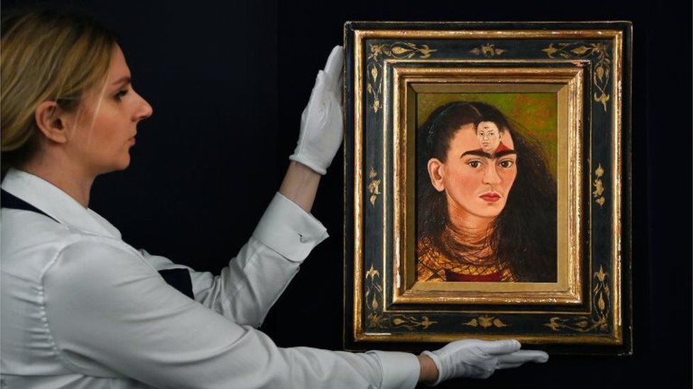 An auction house staff member carries Frida Kahlo's painting 'Diego y Yo'