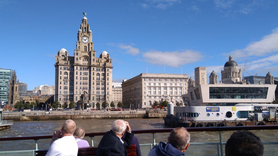passengers on Mersey Ferry look at liver buildings