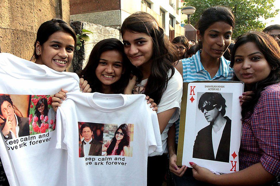 Fans pose with portraits of Indian Bollywood actor Shah Rukh Khan during his 48th birthday celebrations outside his residence in Mumbai on November 2, 2013