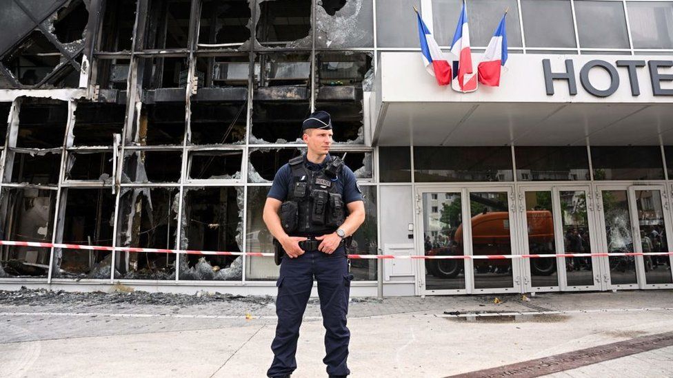 Un agente de policía frente a la fachada quemada del Hotel du ville en Garges-les-Gonesse, al norte de París, el 29 de junio de 2023,
