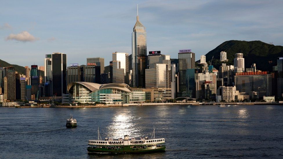 A Star Ferry boat crosses Victoria Harbour in front of a skyline of buildings in Hong Kong.