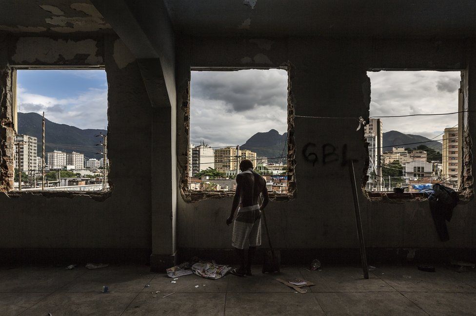 A man stands at the windows of the abandoned Ministry of Finance building (now an occupied building/squat) in the 'Favela' Mangueira community, North Zone, Rio de Janeiro, Brazil