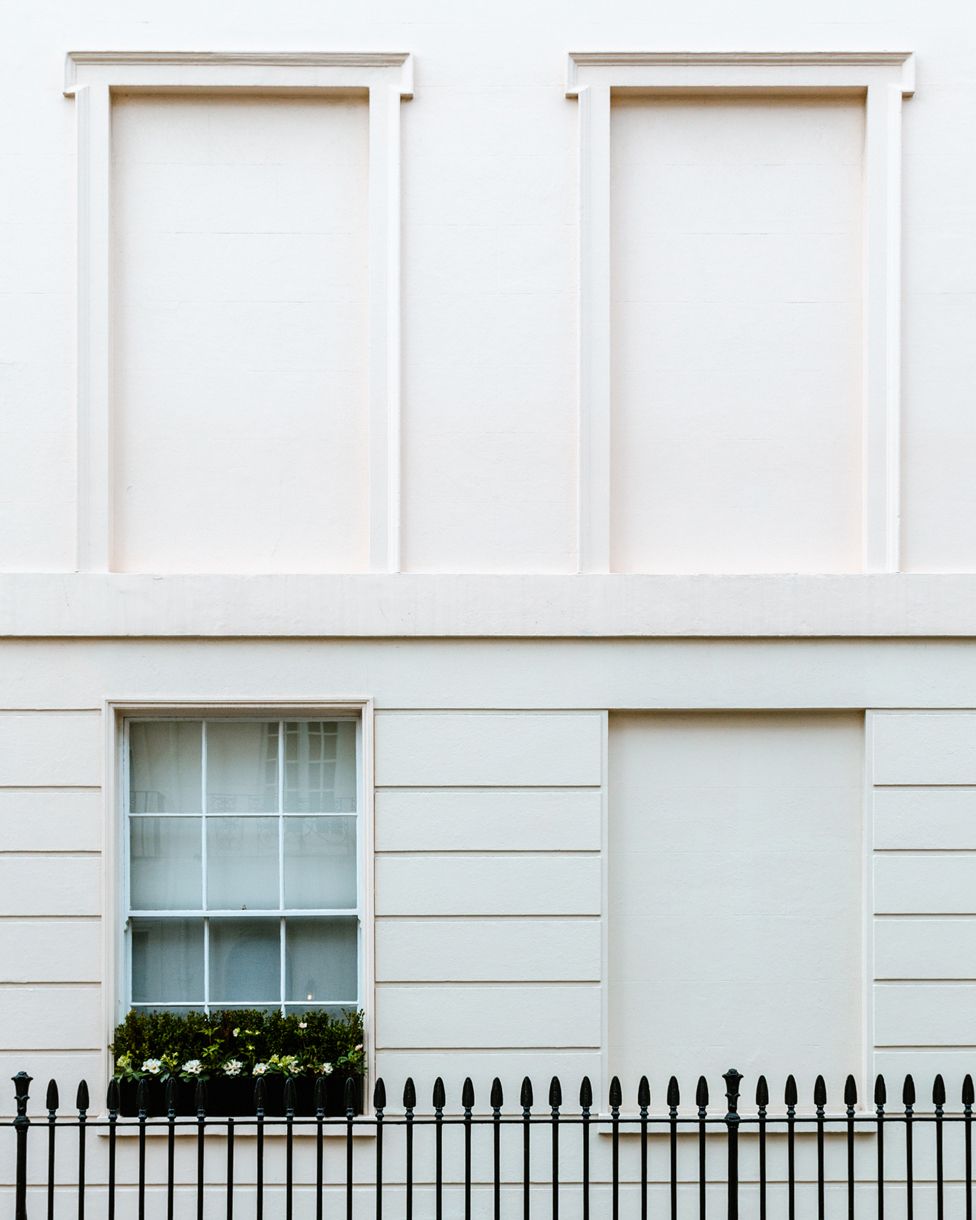 Three blocked windows and one unblocked window on a white building in South Eaton Place, London