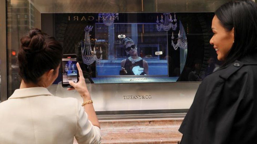 Guests watch as a scene from the movie "Breakfast at Tiffany's" is played in a store window