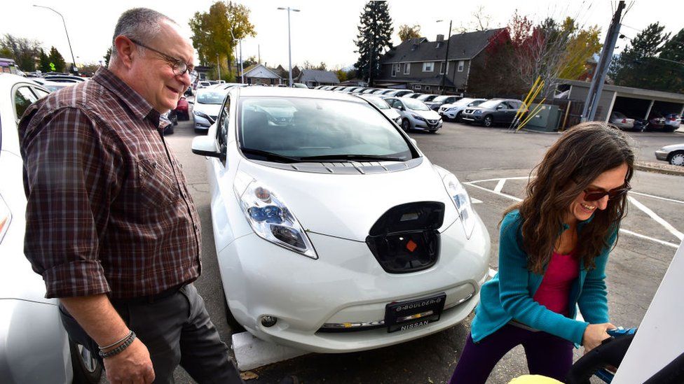 Мужчина и женщина учатся заряжать подержанный электромобиль
