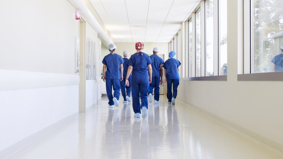 Surgical Team Walking Down Hospital Corridor - Stock Photo