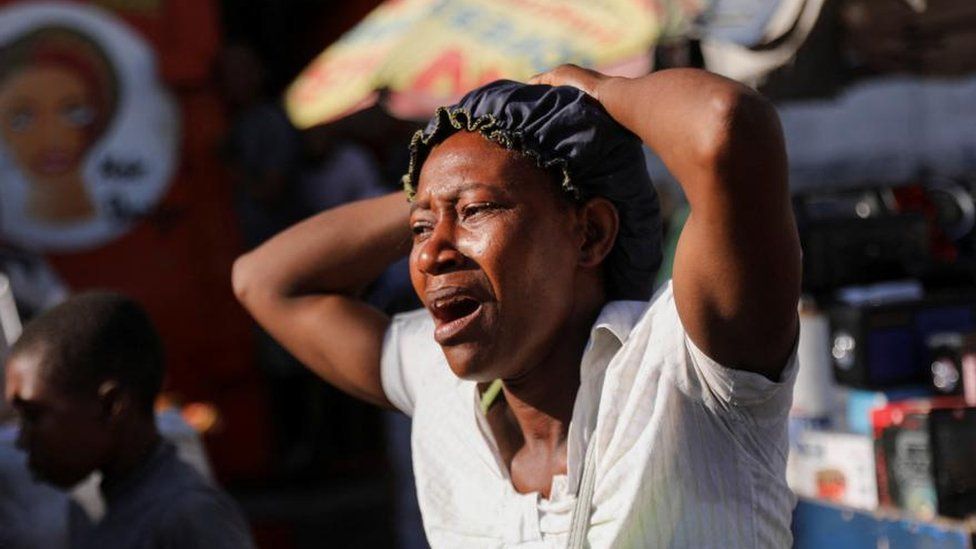A woman reacts at a crime scene where the bodies of several people, who were shot dead earlier in the morning amid an escalation in gang violence, were being removed by an ambulance, in Port-au-Prince, Haiti March 18, 2024.