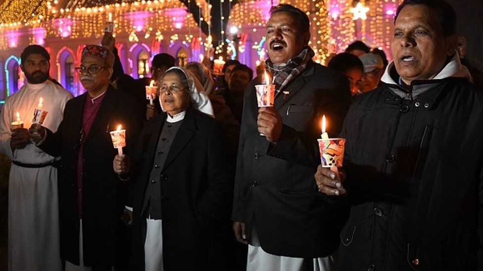Христианские священники вместе с преданными принимают участие в службе при свечах перед рождественскими праздниками в церкви Святого Павла в Амритсаре 22 декабря 2021 г.