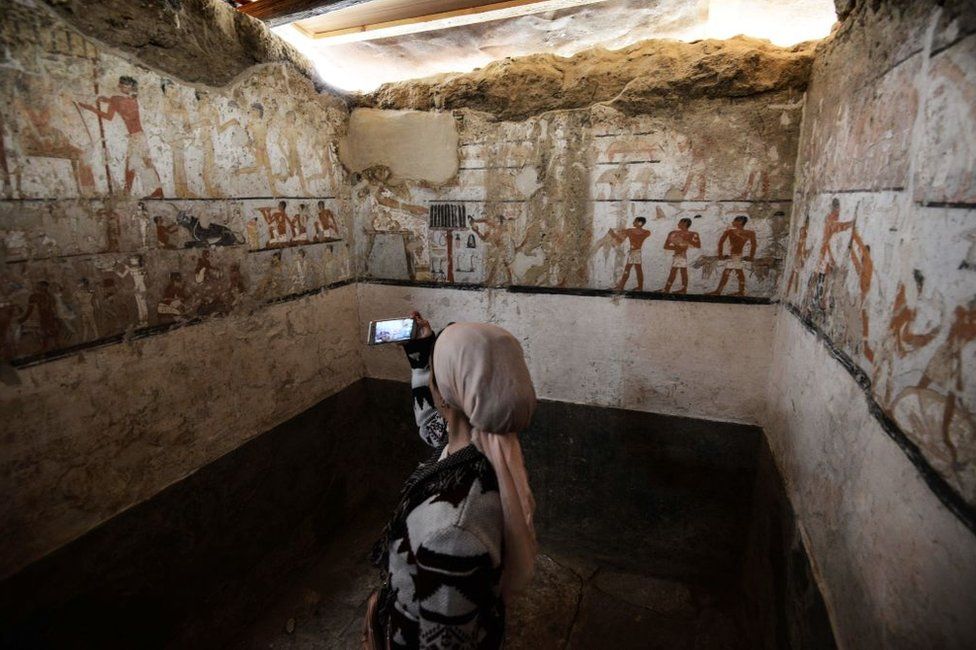 A woman takes a photo inside the tomb of an Old Kingdom priestess adorned with well-preserved and rare wall paintings on the Giza plateau in Cairo that was unveiled on February 3, 2018 after being discovered during excavation work in Giza's western cemetery by a team of Egyptian archaeologists. Antiquities Minister Khaled al-Enany told reporters the tomb belong to Hatpet, a priestess to Hathor, the goddess of fertility who assisted women in childbirth.