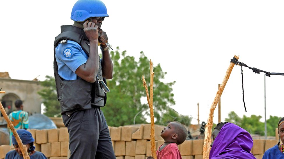 Ein Kind beobachtet einen UN-Friedenssoldaten auf Patrouille durch die Straßen von Gao, Mali - August 2018