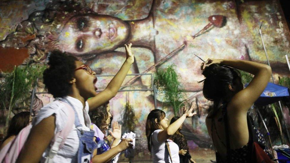 Activists march for pro-choice rights past street art displayed on a wall on September 28, 2017 in Rio de Janeiro, Brazil.