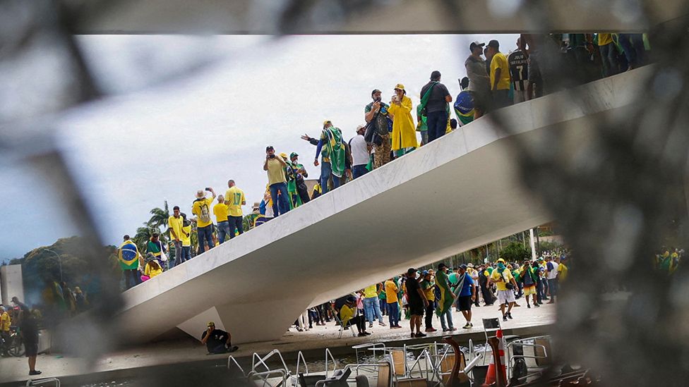 Supporters of Brazil's former President Jair Bolsonaro are pictured through broken glass as they hold a demonstration against President Luiz Inacio Lula da Silva, in Brasilia, Brazil, January 8, 2023