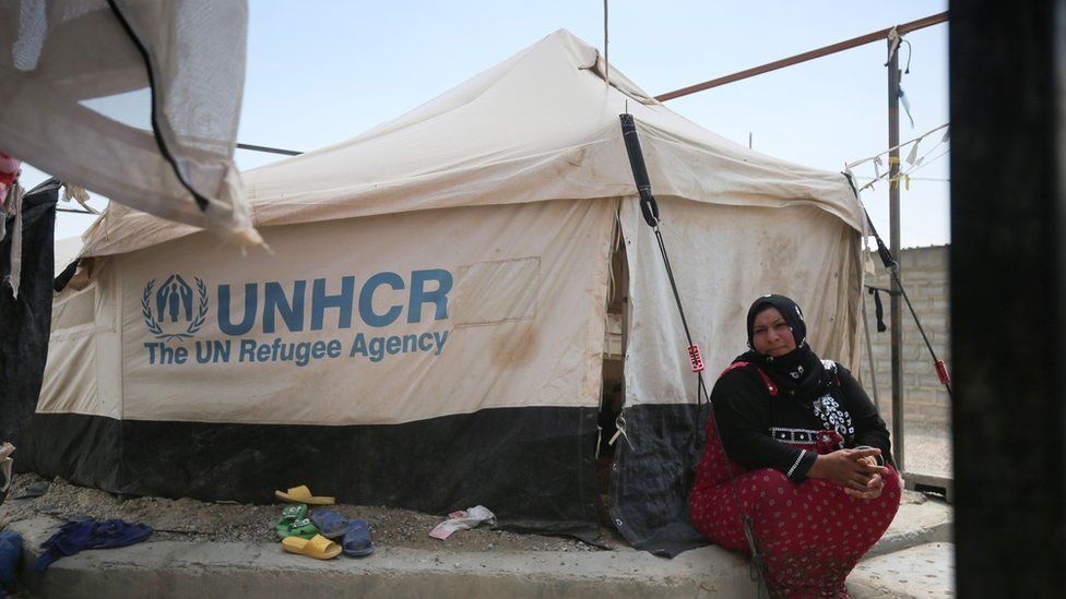 A displaced Iraqi woman sits outside a tent where she is taking shelter in a camp for internally displaced people.