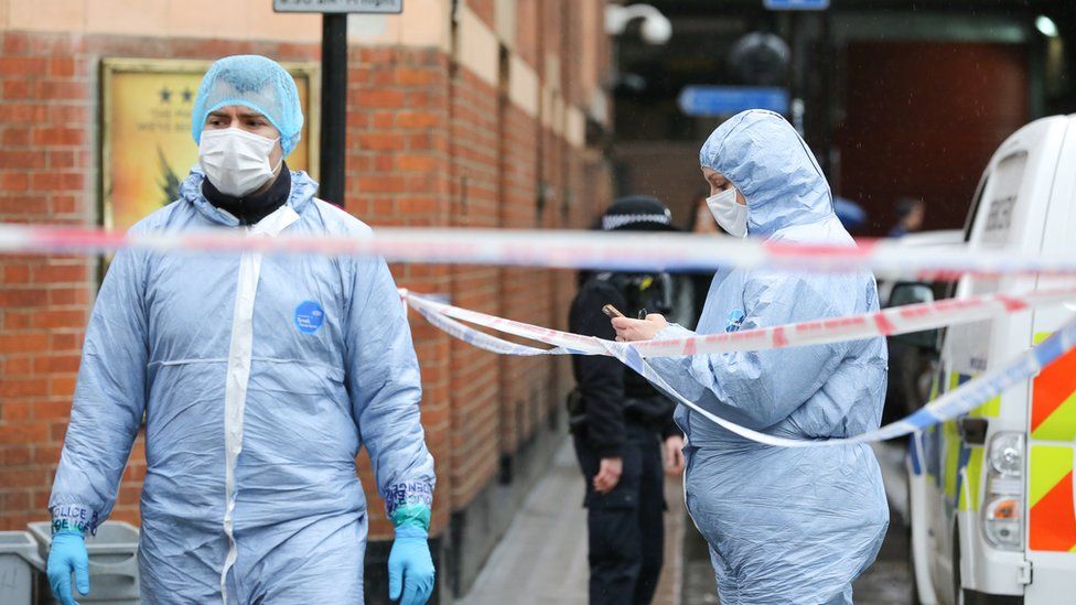 Forensic officers are seen at the crime scene outside The Coach and Horses pub in Romilly Street in Soho