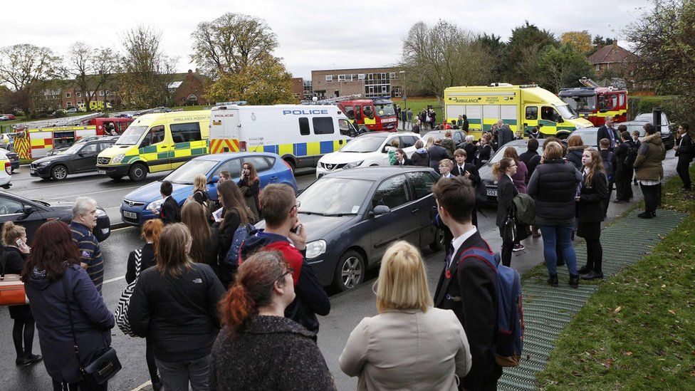 Pupils and staff stand outside Outwood Academy as emergency services attend to an incident at the school