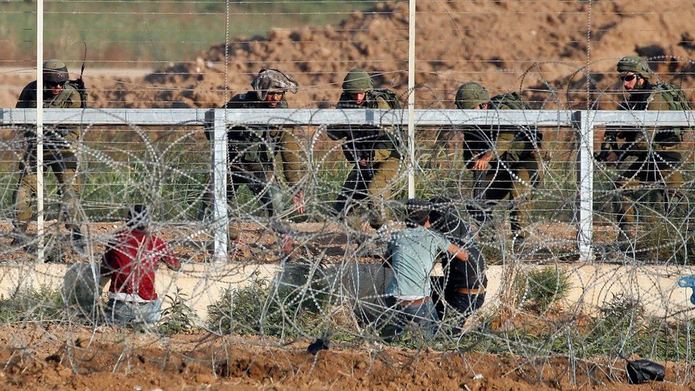 Israeli soldiers arrest three Palestinians who approached the Gaza-Israel border fence during a protest on 15 May 2018