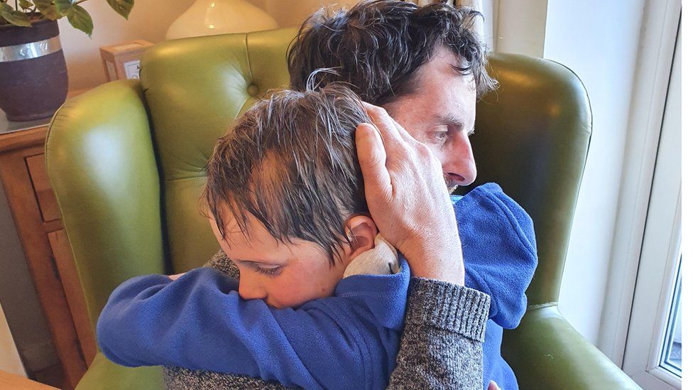 Stephen Landon hugging his son in chair