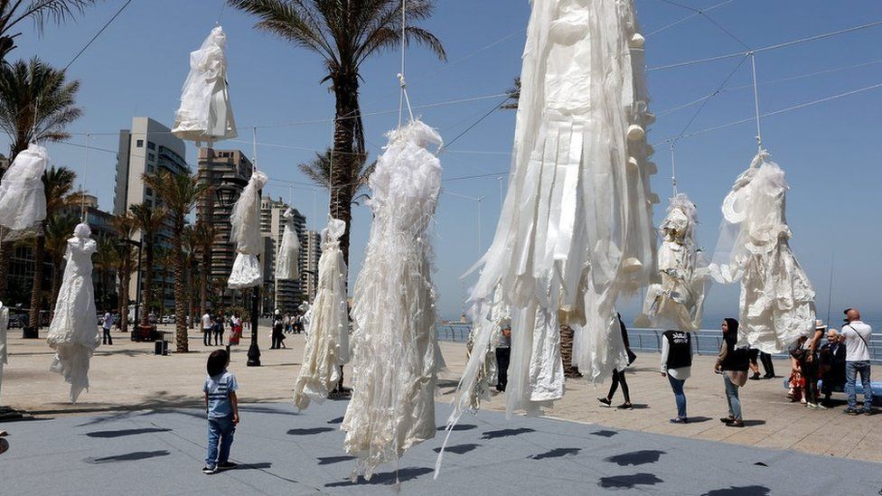 People stand next to an artwork, shows hanging wedding white dresses, to protest against article 522 in the Lebanese penal code, at Ain el Mraysseh Square, Beirut, Lebanon, 22 April 2017