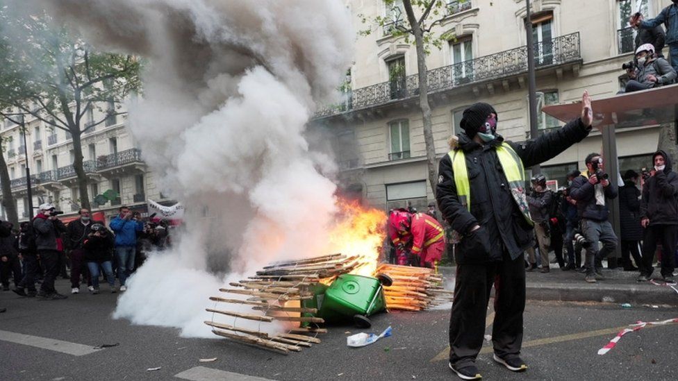 A "Yellow vest" protester gestures near a fire during the traditional May Day protests in France