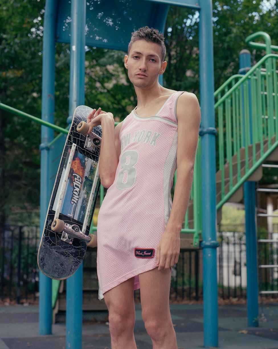 A skateboarder poses whilst wearing a pink sports outfit