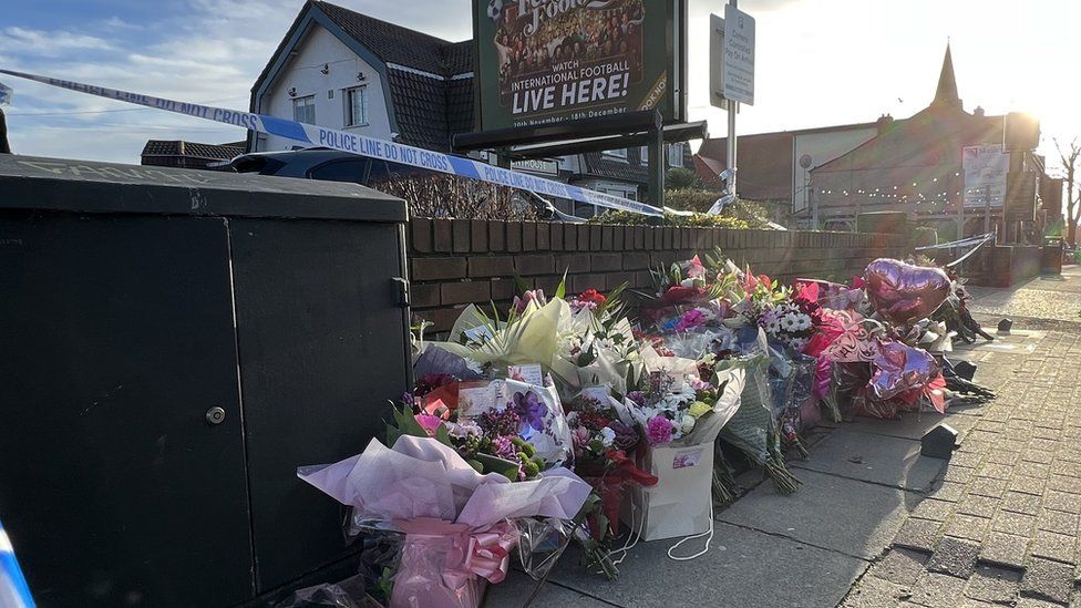 Floral tributes outside a pub within a police tape