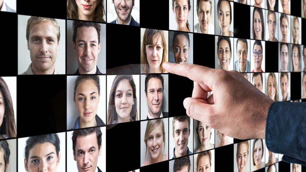 A man pointing to photos of job applicants