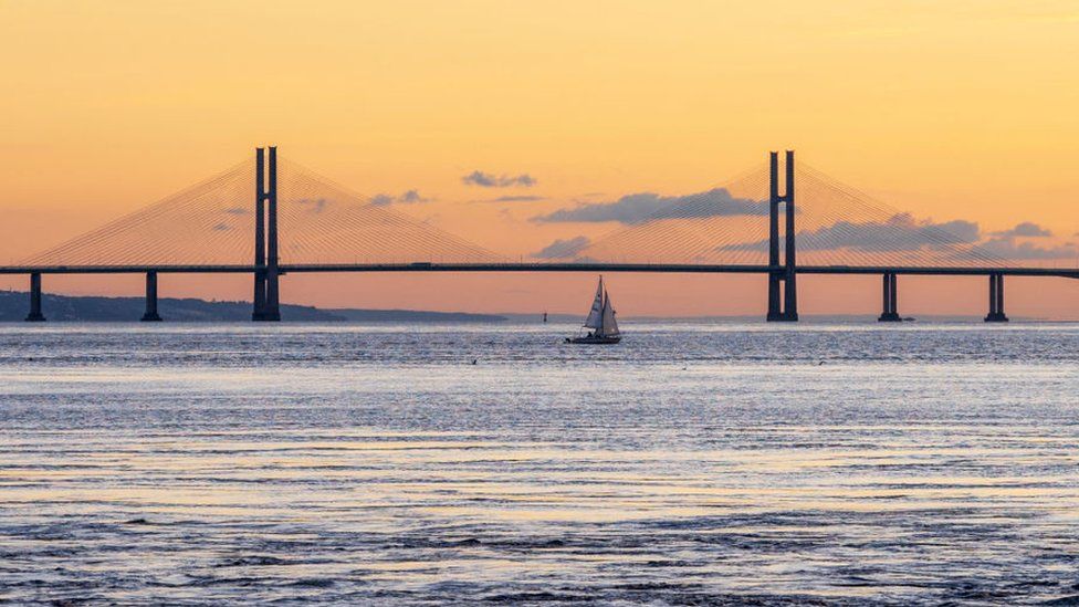 A sailboat passes alongside the Prince of Wales Bridge