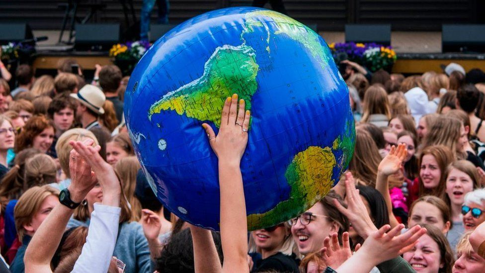 A group of young people hold an inflatable globe