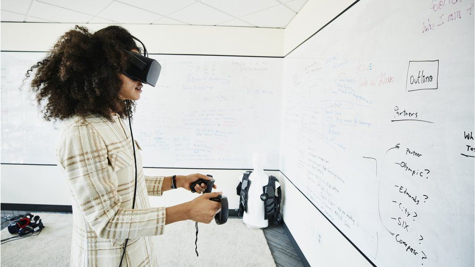 Female engineer testing programme on virtual reality headset in computer lab