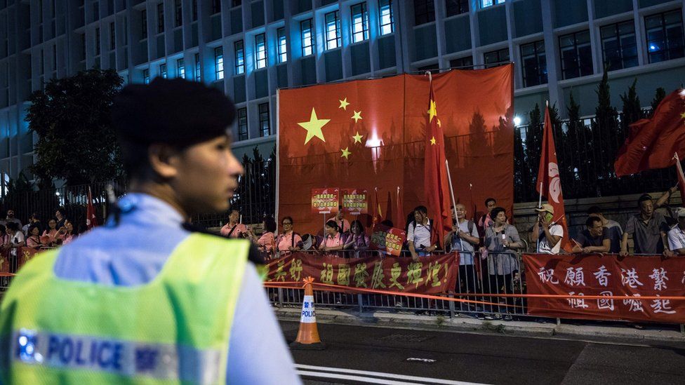 A policeman keeps watch as pro-China supporters gather along a road during a visit by China's President Xi Jinping in Hong Kong on 29 June 2017