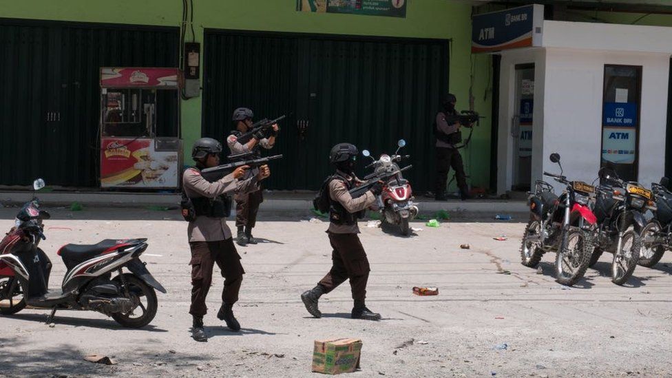 Police fire warning shots outside a shop in Palu, Indonesia