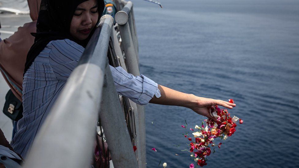 A family of one of the victims of Lion Air flight JT 610 throws flowers on deck of the Indonesian Navy ship, 6 November 2018