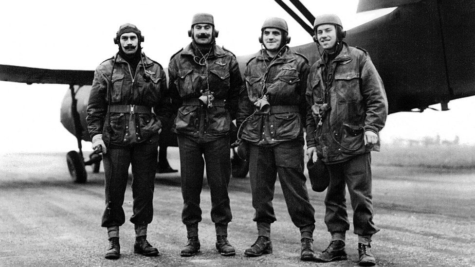 Four WW2 Glider Pilots standing under the wing of a Horsa Glider.