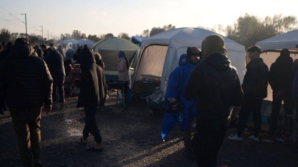 Migrants outside tents in a makeshift camp in Northern France