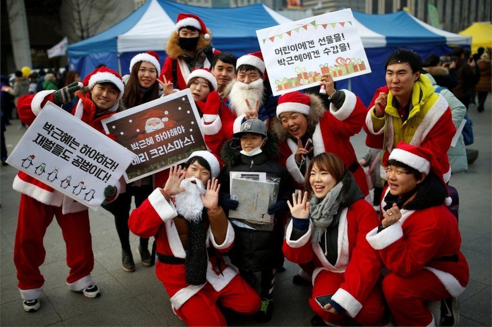South Koreans wearing Santa Claus costumes attend a candlelight protest as they carry placards reading "Park Geun-Hye and Prime Minister Hwang Kyo-ahn Out"