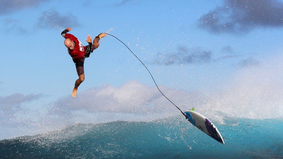 A surfer flies off his board