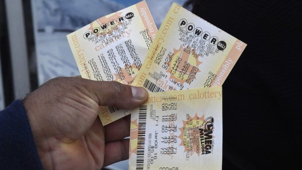 A man holds out his Powerball lottery tickets and a MegaMillions lottery ticket outside Kavanagh Liquors in San Lorenzo, California (08 January 2016)