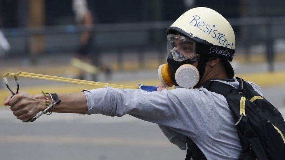A protester fires a sling-shot during violent clashed in Venezuela