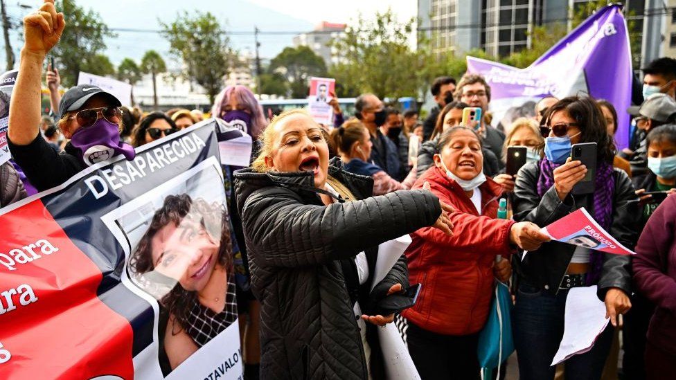 A crowd of protesters, many of them women, display banners and protest in Quito
