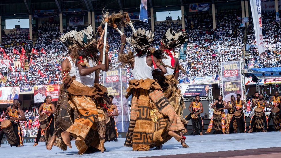 People dancing in costumes in the middle of a stadium full of people