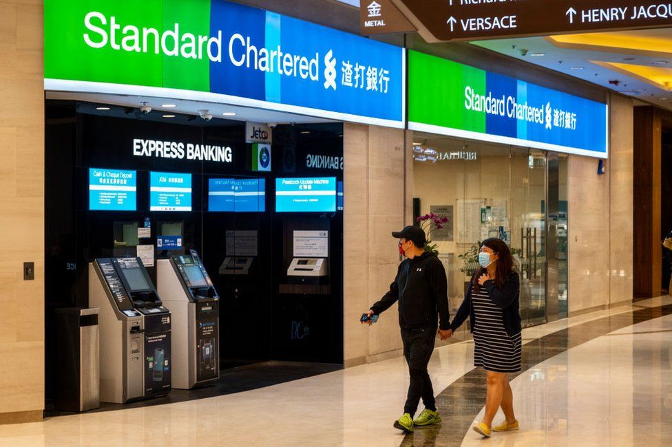 Couple walk past a Standard Chartered branch