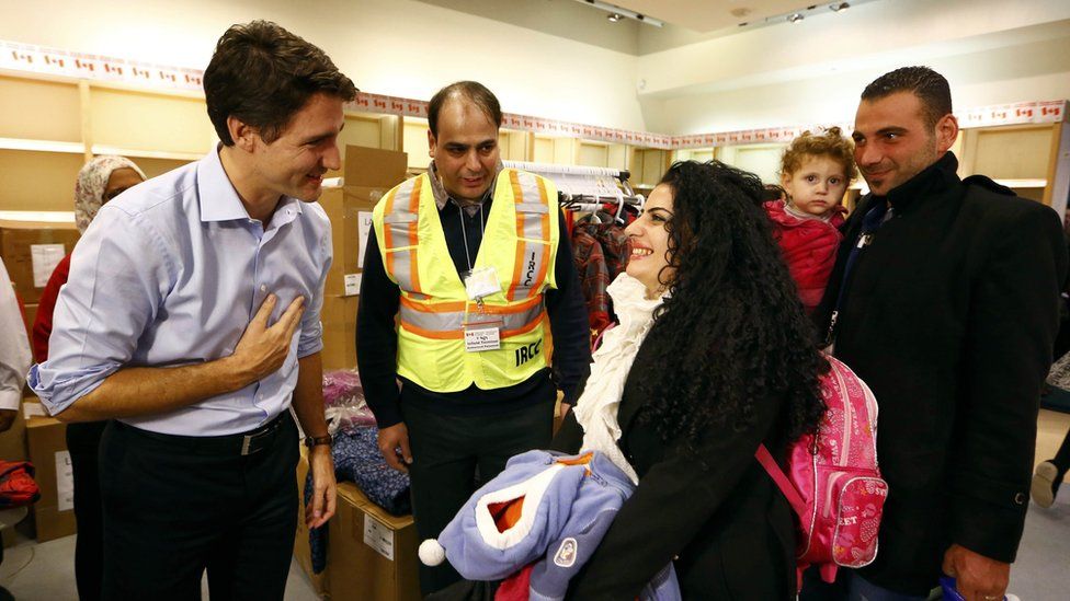 Syrian refugees are greeted by Canada"s Prime Minister Justin Trudeau (L) on their arrival from Beirut at the Toronto Pearson International Airport