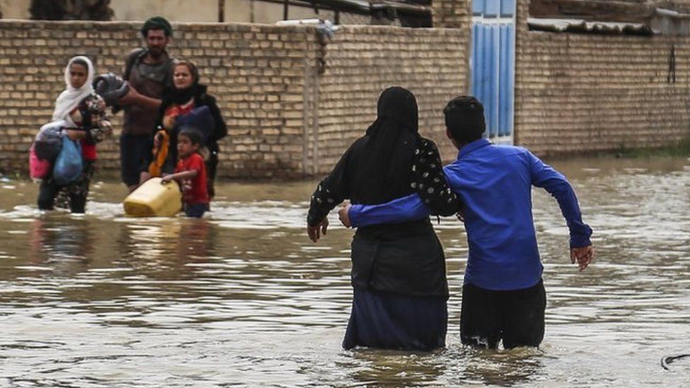 Iranians walk through floodwaters after unprecedented rains, March 2019