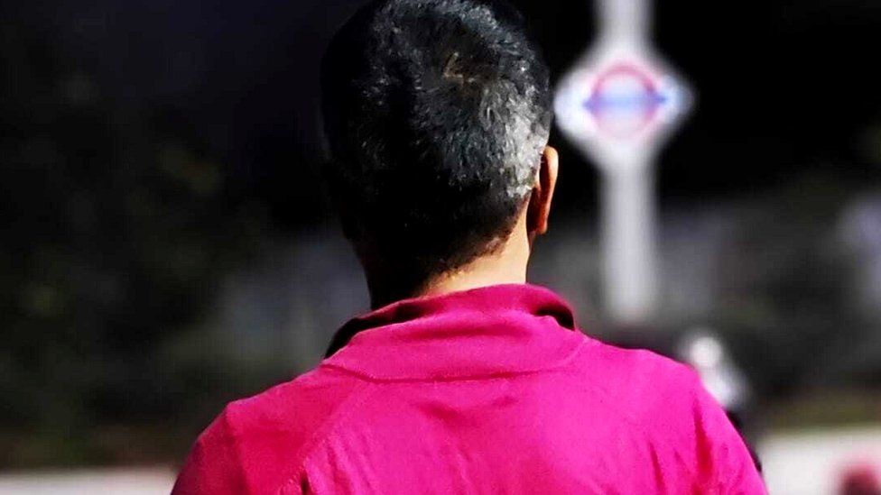 The back of a man's head wearing a pink shirt