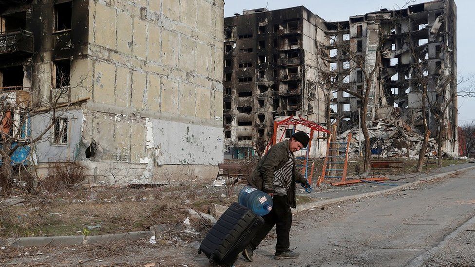A man walks past a destroyed building in Mariupol