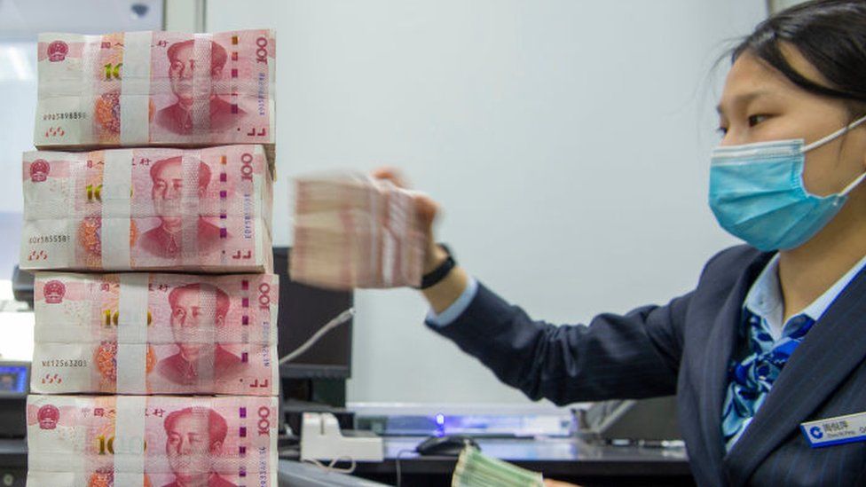 Banker worker counts Chinese currency notes.